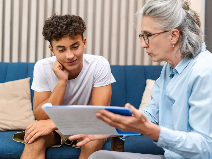 Teenage boy reviewing a treatment plan with a clinician during an adolescent mental health session
