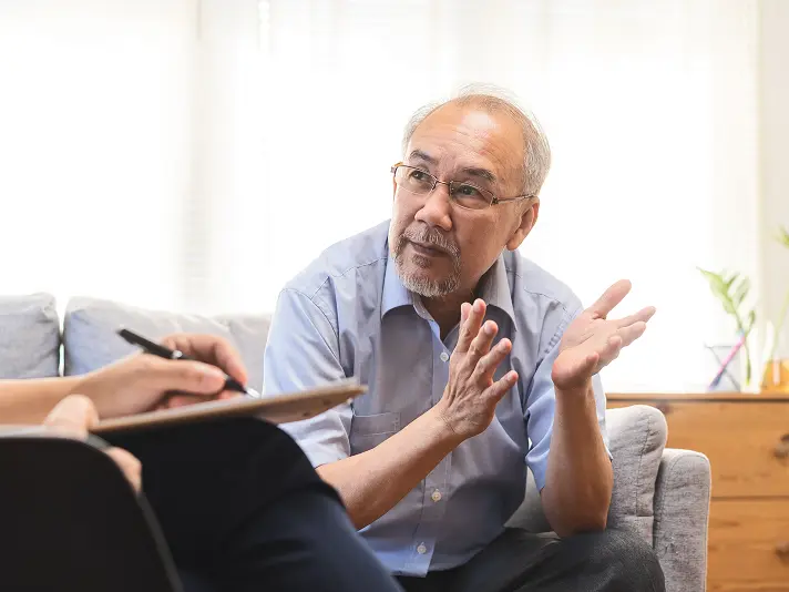 Older man talking with a therapist who takes notes during an individual therapy session