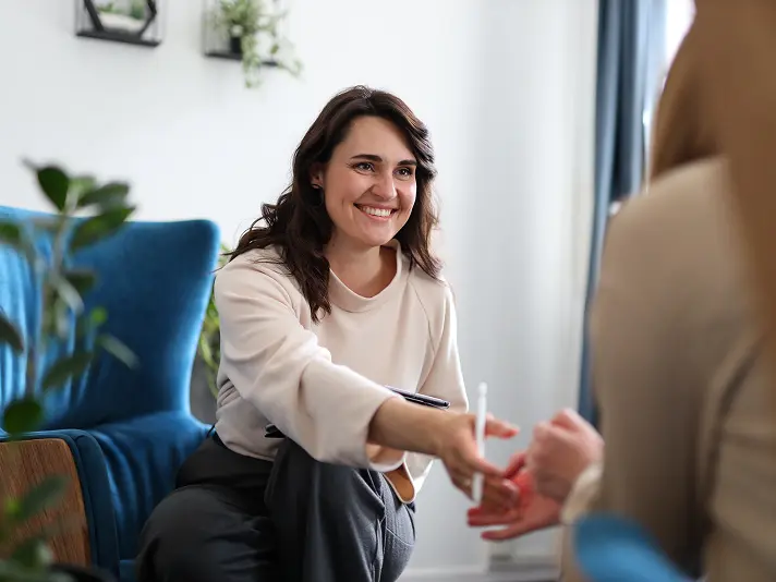 Smiling psychiatric provider reaching out to greet a patient at the start of an appointment